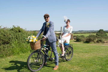 Bride and groom riding a tandem bike in the sunshine on wedding day