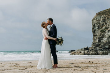 Bride and groom kissing on beach in Cornwall
