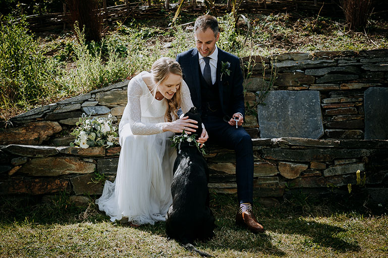 Bride and groom with black labrador dog on wedding day