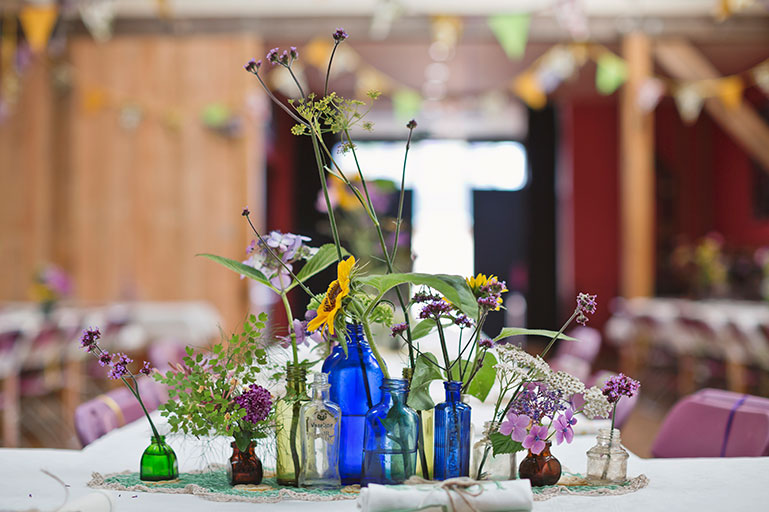 Vintage coloured glass bottles and cottage garden flowers wedding decor